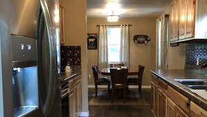 A modern kitchen with stainless steel appliances, wooden cabinets, and a farmhouse-style dining area. - Lake Texoma! Beautiful Cabin with Relaxing atmosphere!sleeps 5 (Gordonville)