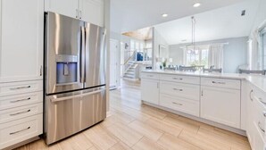 Una cocina moderna con armarios blancos, un refrigerador de acero inoxidable y piso de madera.