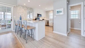 Una cocina moderna con una isla central, taburetes de bar y un comedor con mesa y sillas.