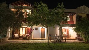 A two-story house with a stone patio, outdoor furniture, and a table. - Avista Villa (Sithonia)