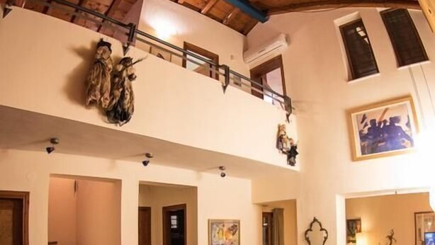 A spacious living area with a high wooden ceiling, a staircase, a sofa, a coffee table, and a dining table. - Avista Villa (Sithonia)