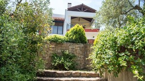 A stone staircase leading up to a modern house with a stone wall and lush greenery. - Avista Villa (Sithonia)