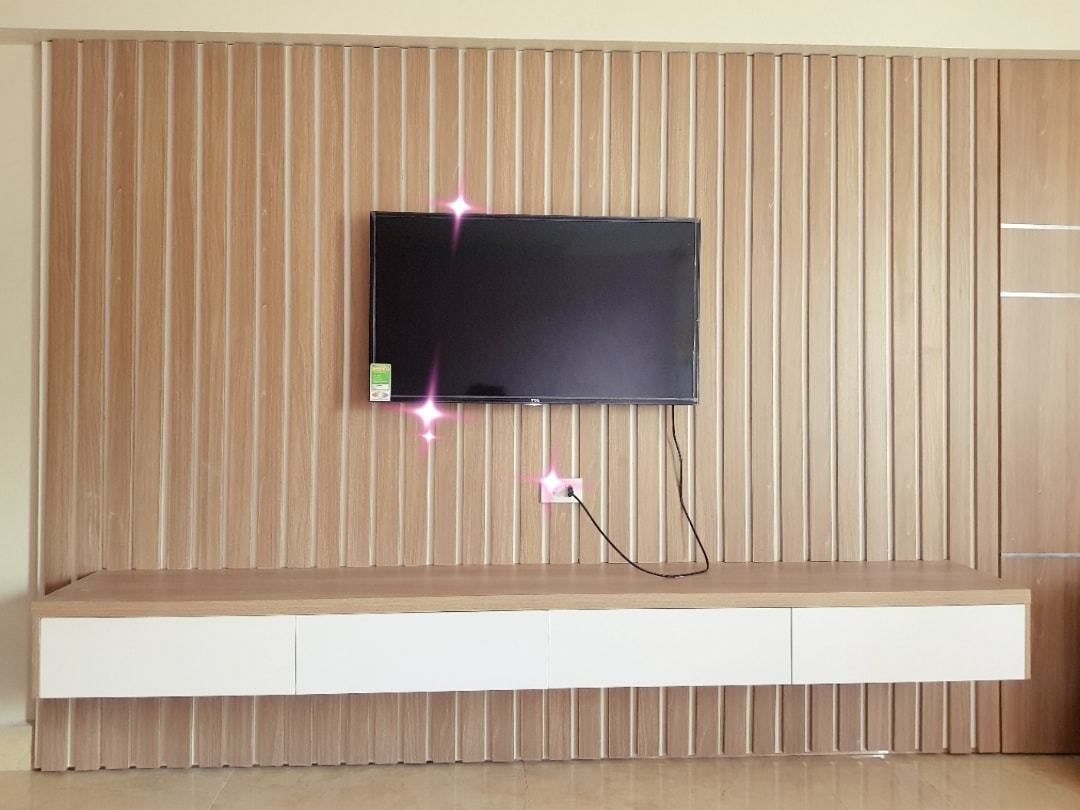 Televisor de pantalla plana montado en una pared de madera con un mueble bajo.