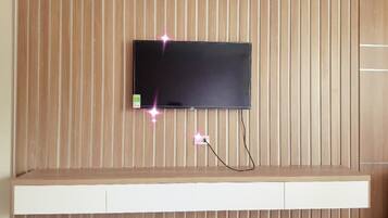 A flat-screen TV mounted on a wooden wall with a white entertainment unit below.