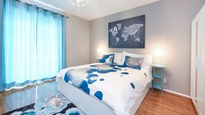 A bedroom with a bed, a world map artwork, a nightstand, and a floor lamp. - Apartment Lali - Apartment with Balcony (Zadar)