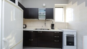 A kitchen with a white refrigerator, black cabinets, a white stove, and a window above the sink. - Apartment Lali - Apartment with Balcony (Zadar)