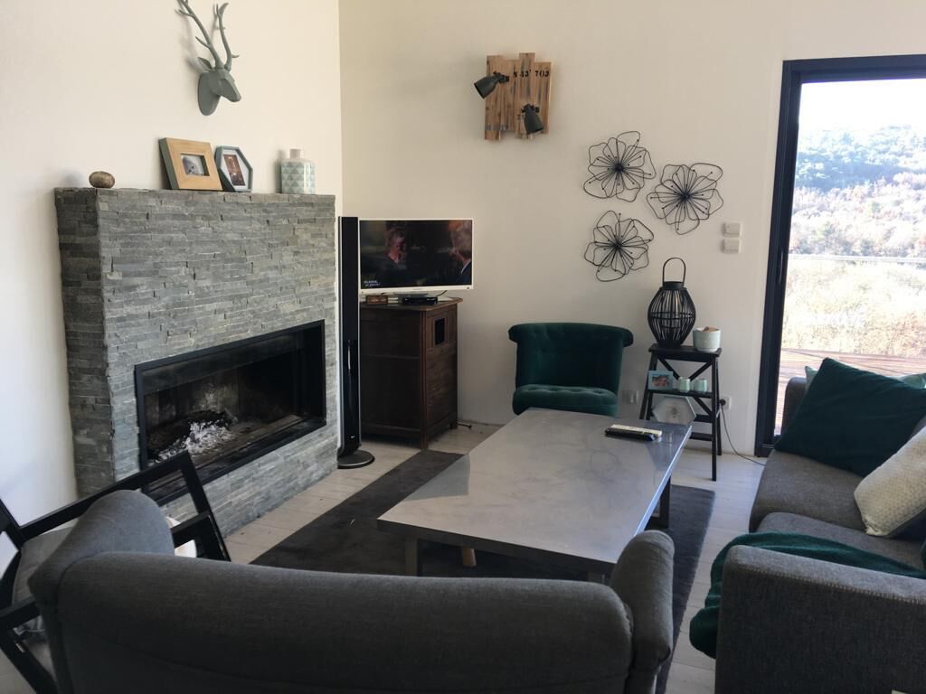 Een woonkamer met een open haard, een televisie, een eettafel en een bank.