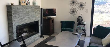 Een woonkamer met een open haard, een televisie, een eettafel en een bank.