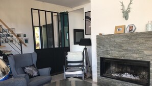 Una sala de estar con chimenea, un sofá, una mesa de centro y una silla.