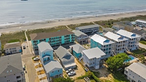 A coastal residential area with multi-story buildings, a beach, and a clear sky. - "Sand Dollar Suites" suite 6: A short stroll from our sandy shores! (Carolina Beach)