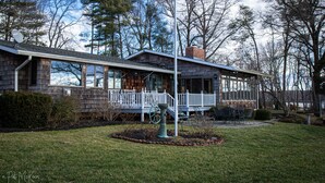 A two-story house with a covered porch, a satellite dish, and a well-maintained lawn. - Nancy’s Touch, A Waterfront Paradise! (North East)