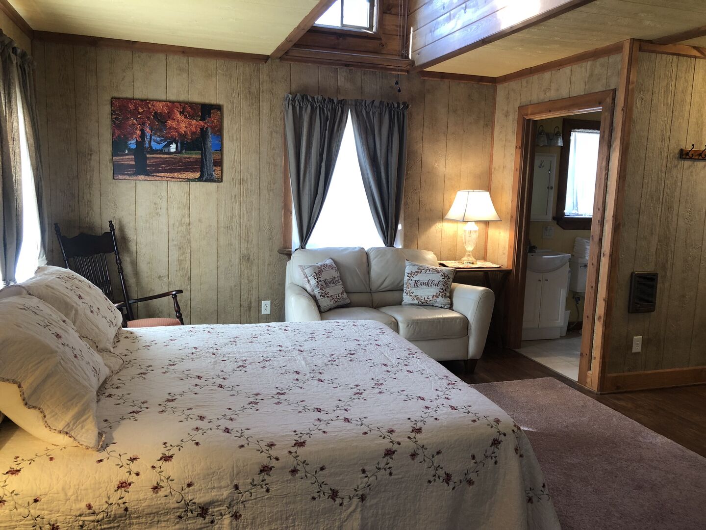 Un dormitorio con una cama grande, una silla, una lámpara y un cuadro en la pared.