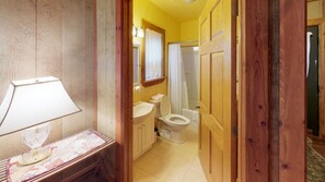 A bathroom with a wooden vanity, a sink, a toilet, and a shower.