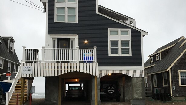 Une maison à deux étages dotée d’un balcon, d’une allée couverte et d’un escalier en bois menant à l’entrée.