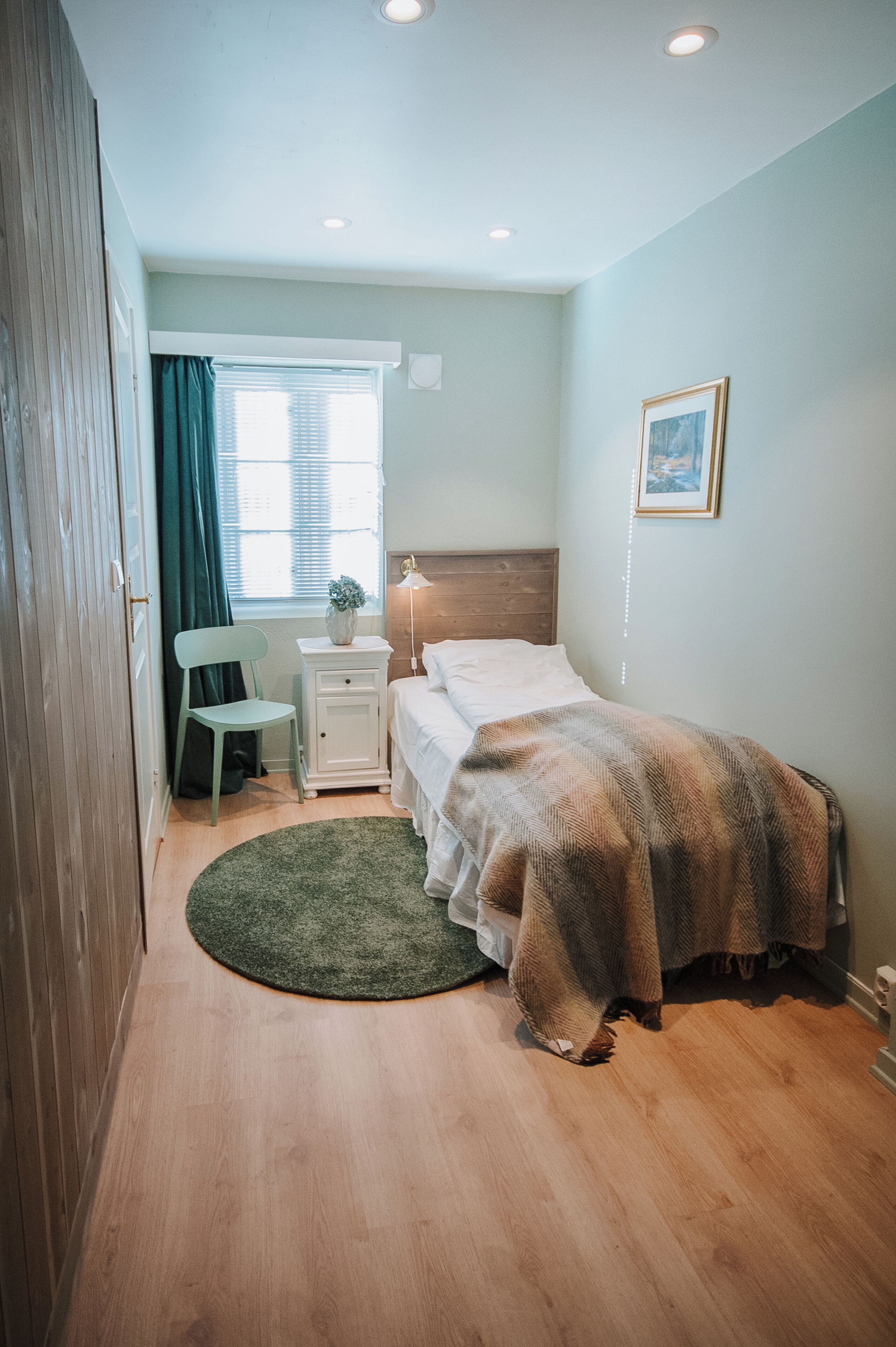 A bedroom with a bed, a desk, a chair, and a window with curtains.