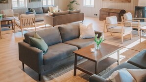 Amplia sala de estar con techo alto, vigas de madera y chimenea. Cuenta con varias zonas de estar con sofás y sillones.