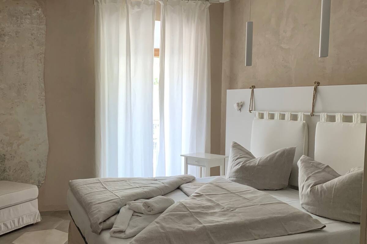 Ein Schlafzimmer mit einem Bett, einem Nachttisch und einem Fenster mit Vorhängen.