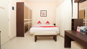 A bedroom with a bed, a bench, a desk, a mirror, a picture on the wall, and a door. - Hotel O Menjangan Residence at Citraland 1 (Surabaya)