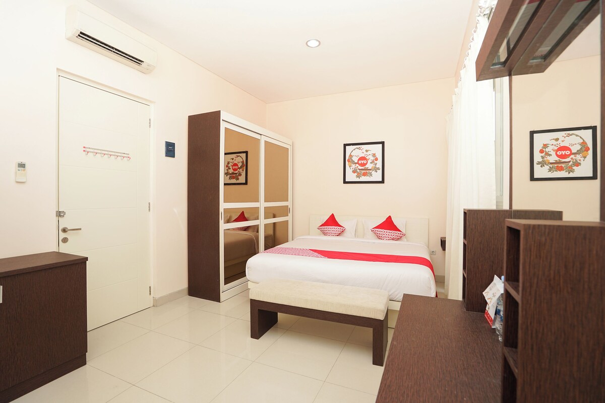 A hotel room with a bed, a wardrobe, a bench, and a bedside table.