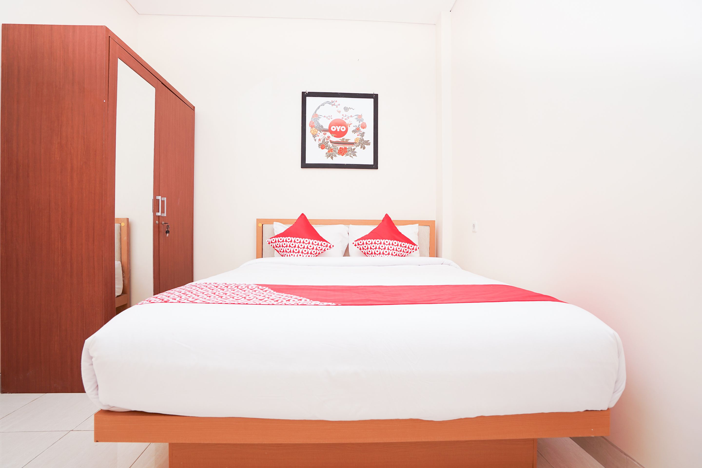 Une chambre à coucher avec un lit en bois, du linge de lit blanc et des oreillers rouges.