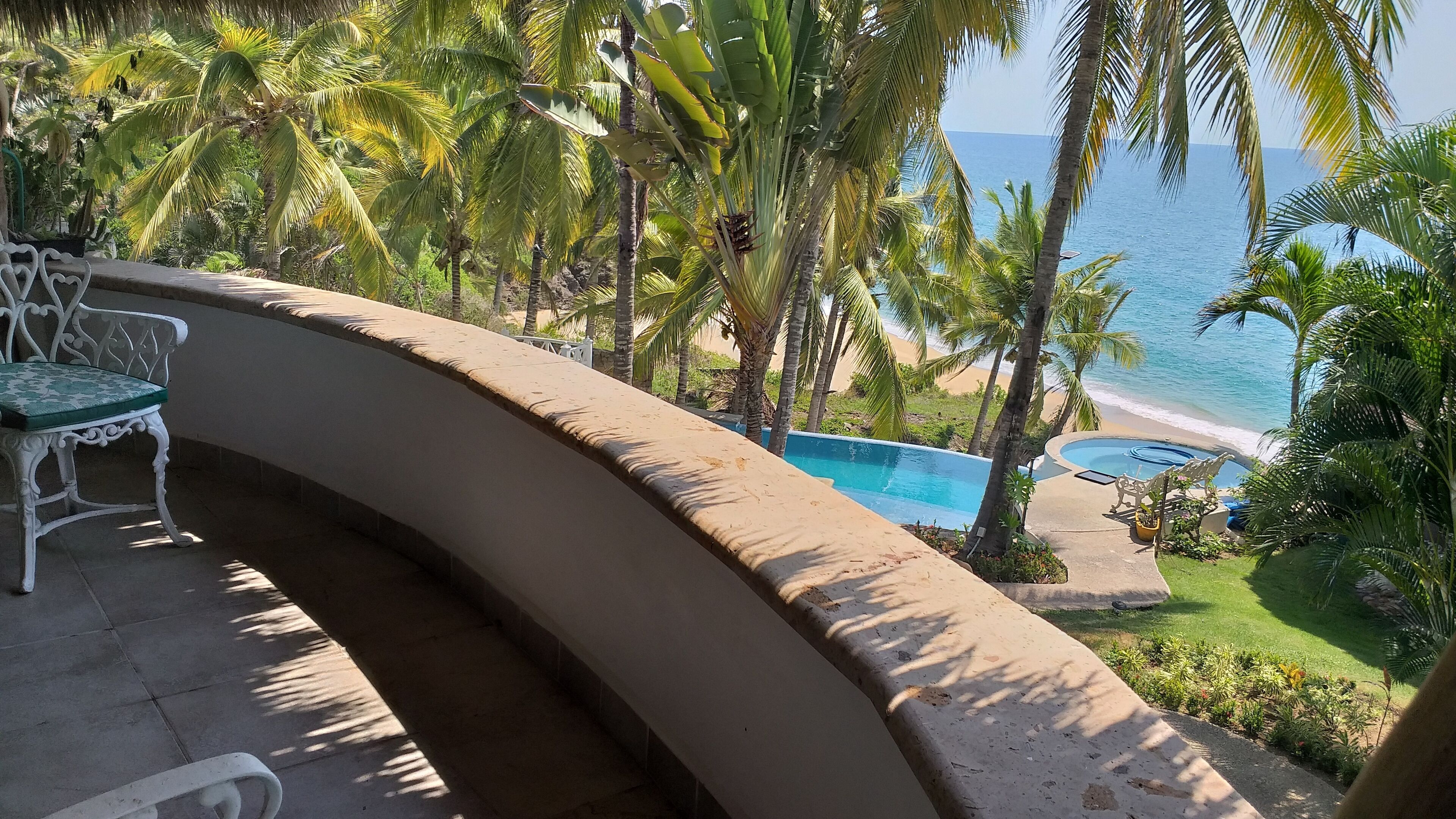 Un balcon avec une piscine, des palmiers et une vue sur la plage.