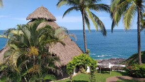 A thatched-roof structure with a view of the ocean. - Bungalows Lydia (San Francisco)