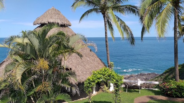 A thatched-roof structure with a view of the ocean. - Bungalows Lydia (San Francisco)
