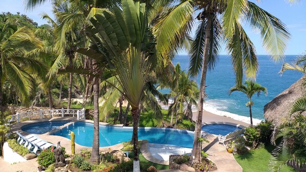 A pool area with a view of the ocean, surrounded by palm trees and a white fence. - Bungalows Lydia (San Francisco)