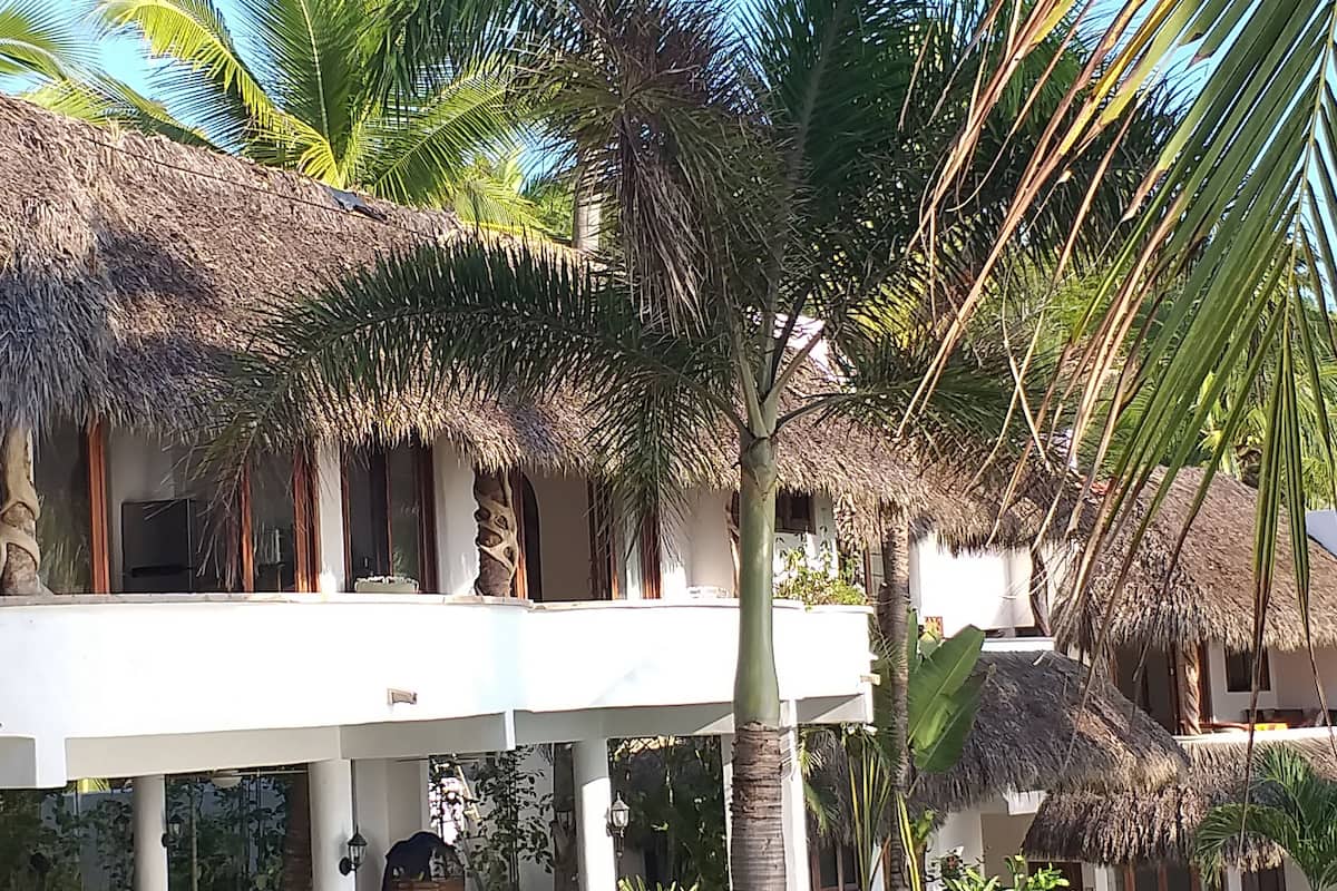 A two-story building with a thatched roof, white walls, and a balcony.