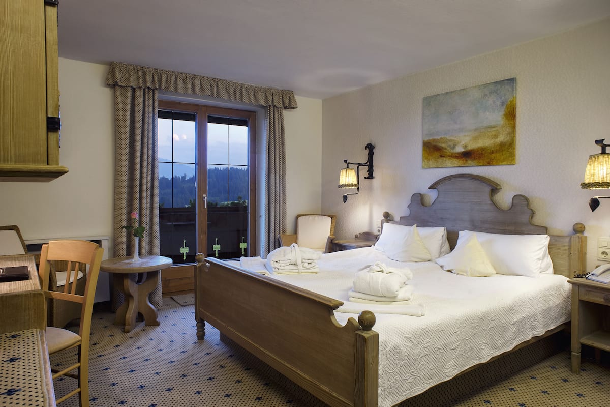Un cuarto de hotel con una cama grande, un escritorio, una silla y vistas al exterior a través de una ventana.