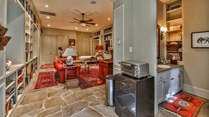A spacious living room with a fireplace, a dining area, and a kitchen with a built-in toaster. - Artist’s Library; Private Swimming Pool in River Oaks Area (Houston)