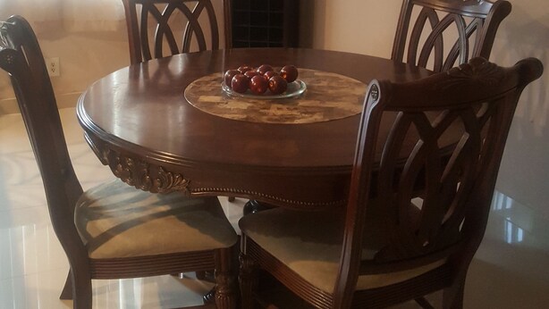 A dining room with a round wooden table, four chairs, and a decorative wall piece. - Beautiful home in the quiet neighborhood (Coral Springs)