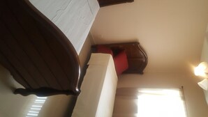 A corner of a room with a wooden chair, a white cushion, and a red pillow on a white headboard. - Beautiful home in the quiet neighborhood (Coral Springs)