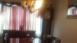 A dining room with a wooden table and chairs, a chandelier, and a clock on the wall. - Beautiful home in the quiet neighborhood (Coral Springs)