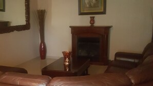 A living room with a brown leather sofa, a wooden coffee table, a fireplace, a ceiling fan, and a framed picture on the wall. - Beautiful home in the quiet neighborhood (Coral Springs)