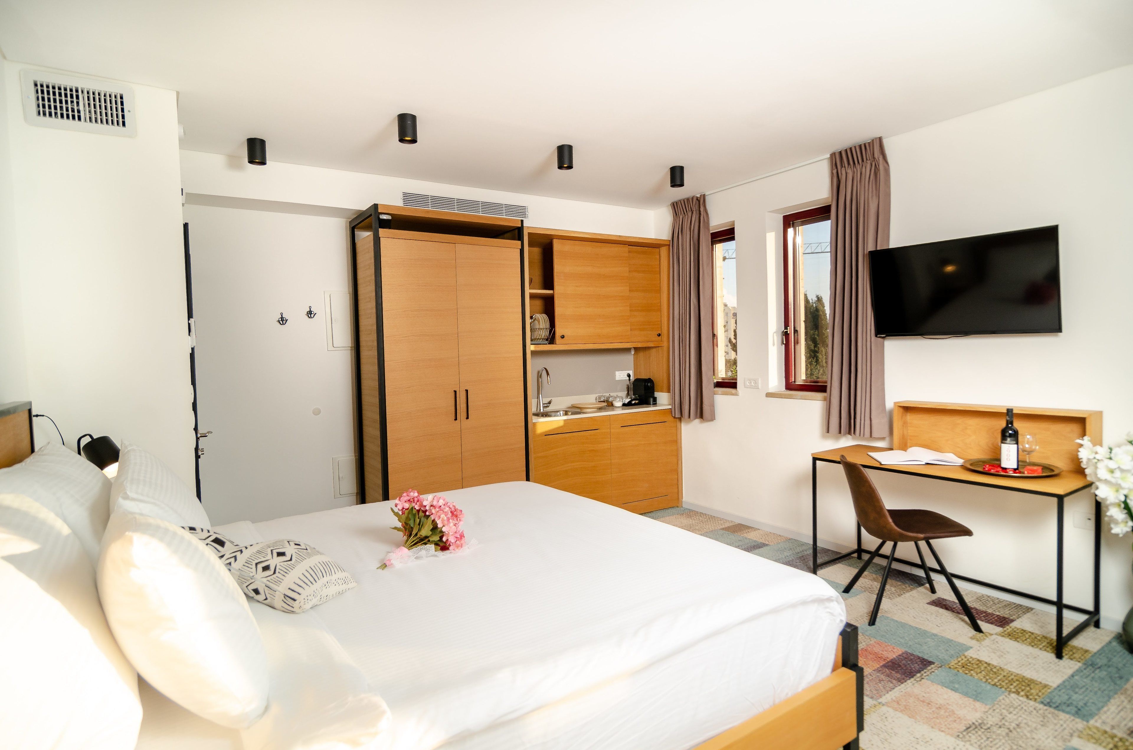 A hotel room with a bed, a desk, a TV, and a wardrobe.