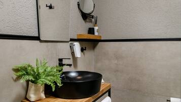 A modern bathroom with a black sink, wooden vanity, and a mirror.