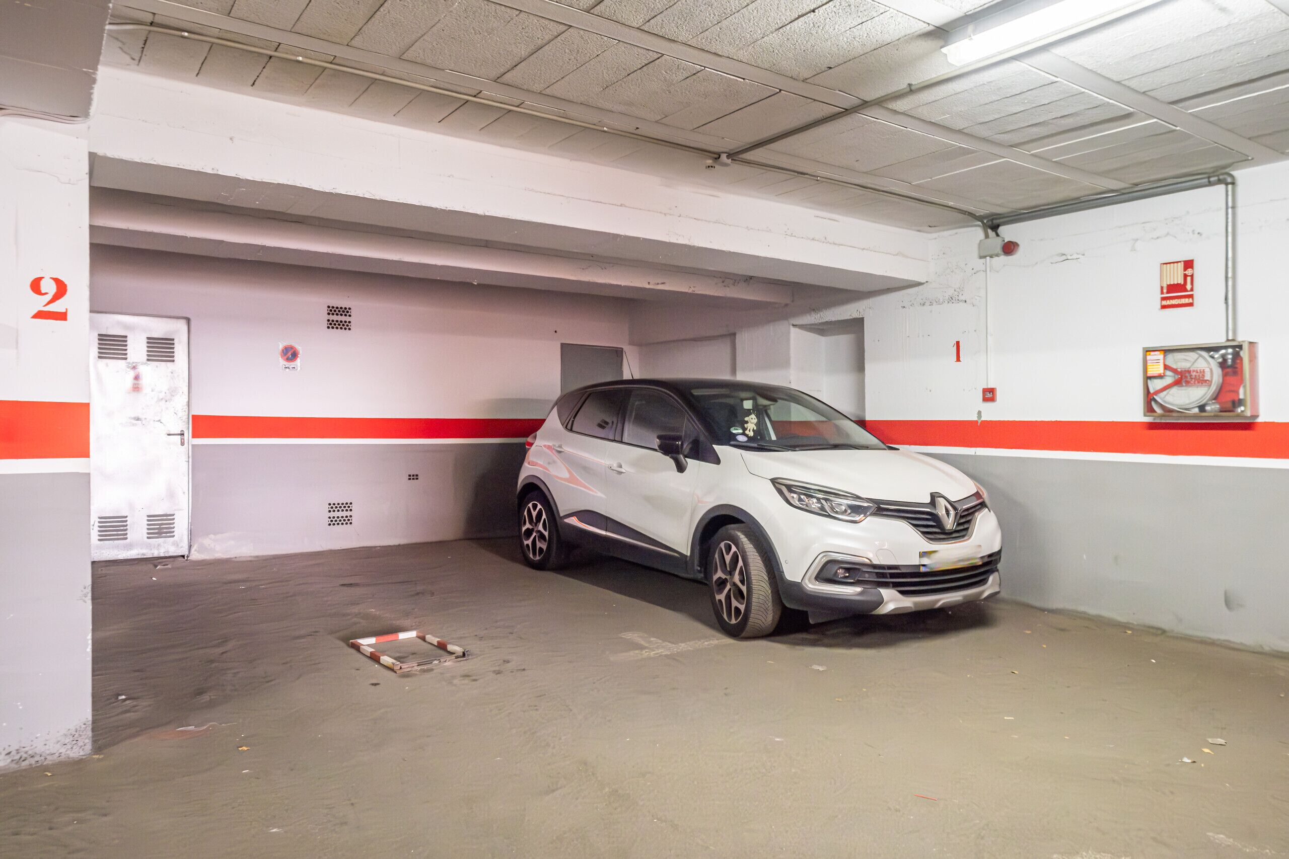 Un parcheggio sotterraneo con un'auto bianca parcheggiata in uno stallo riservato.