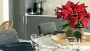 A dining table with a potted red plant, two clear glasses, and a wooden bowl. - UNFINY APARTMENT by the sea (QUARTEIRA)