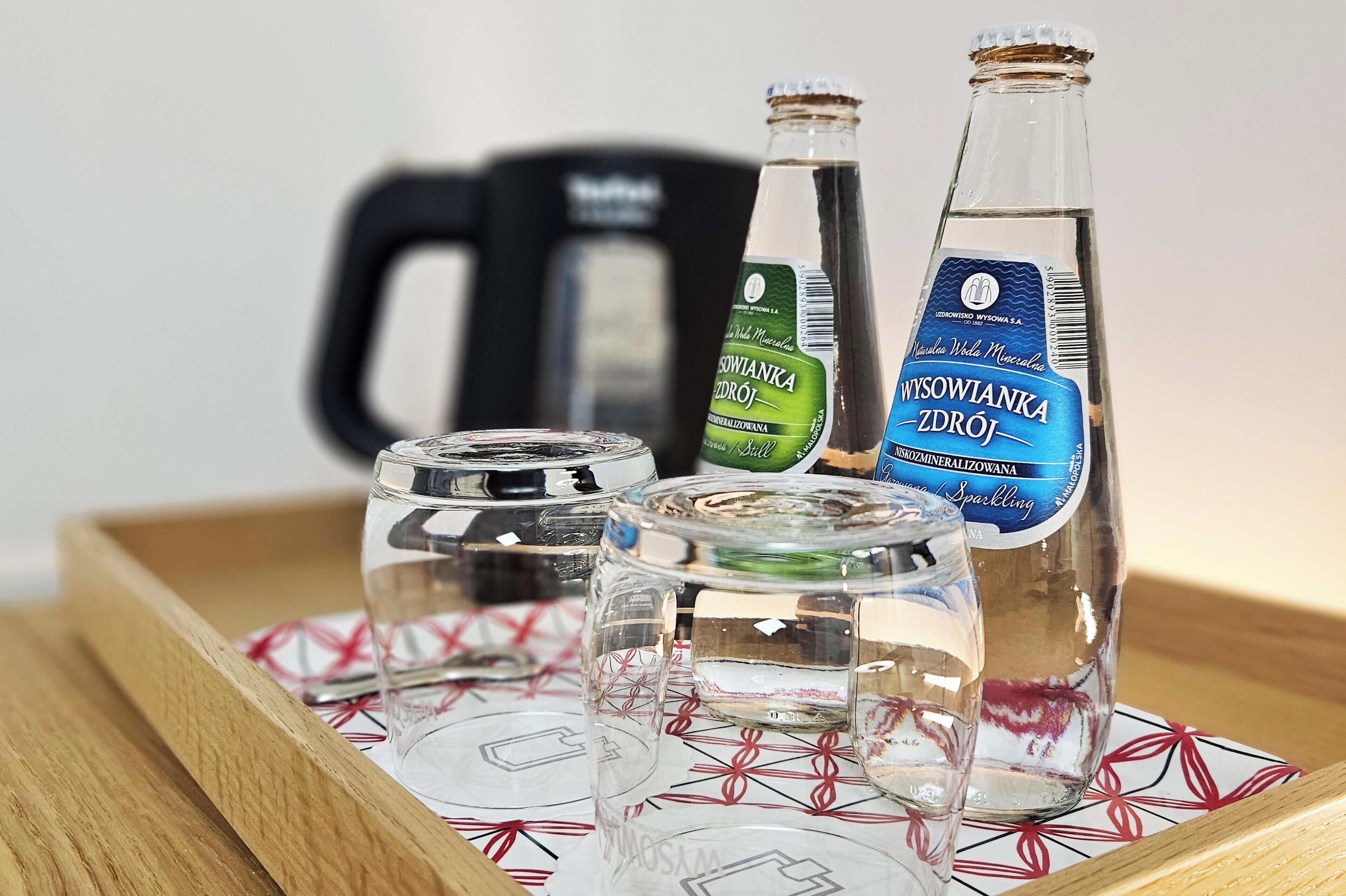 Ein Tablett mit einer Flasche WYSOWIANKA ZDRÓJ, einem Glas und einem Glas mit rotem Muster.