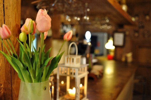 A vase with pink tulips on a wooden surface. - Hotel PROTEA (Boleslawiec)