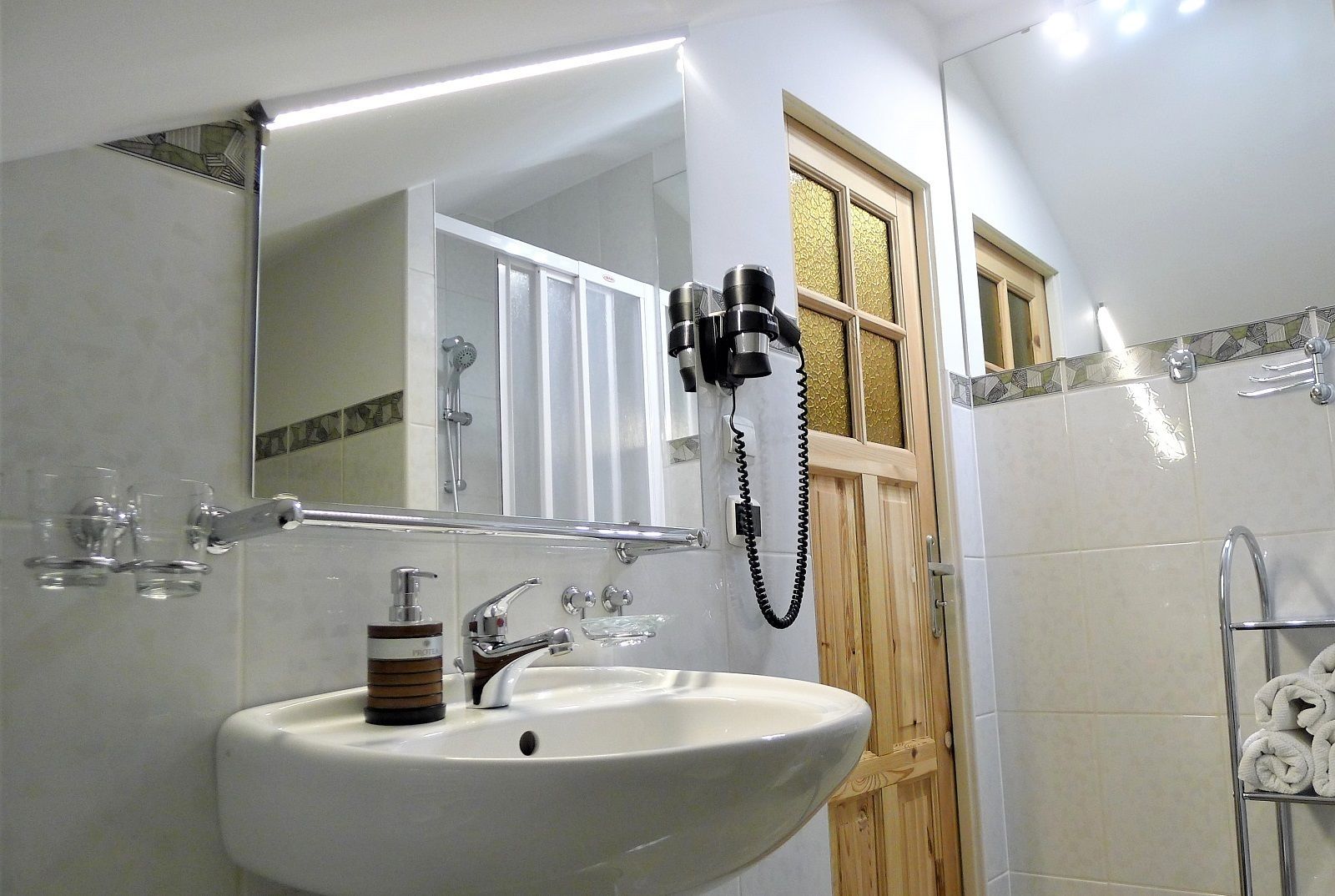 A bathroom with a white sink, a mirror, a shower, and a towel rack.