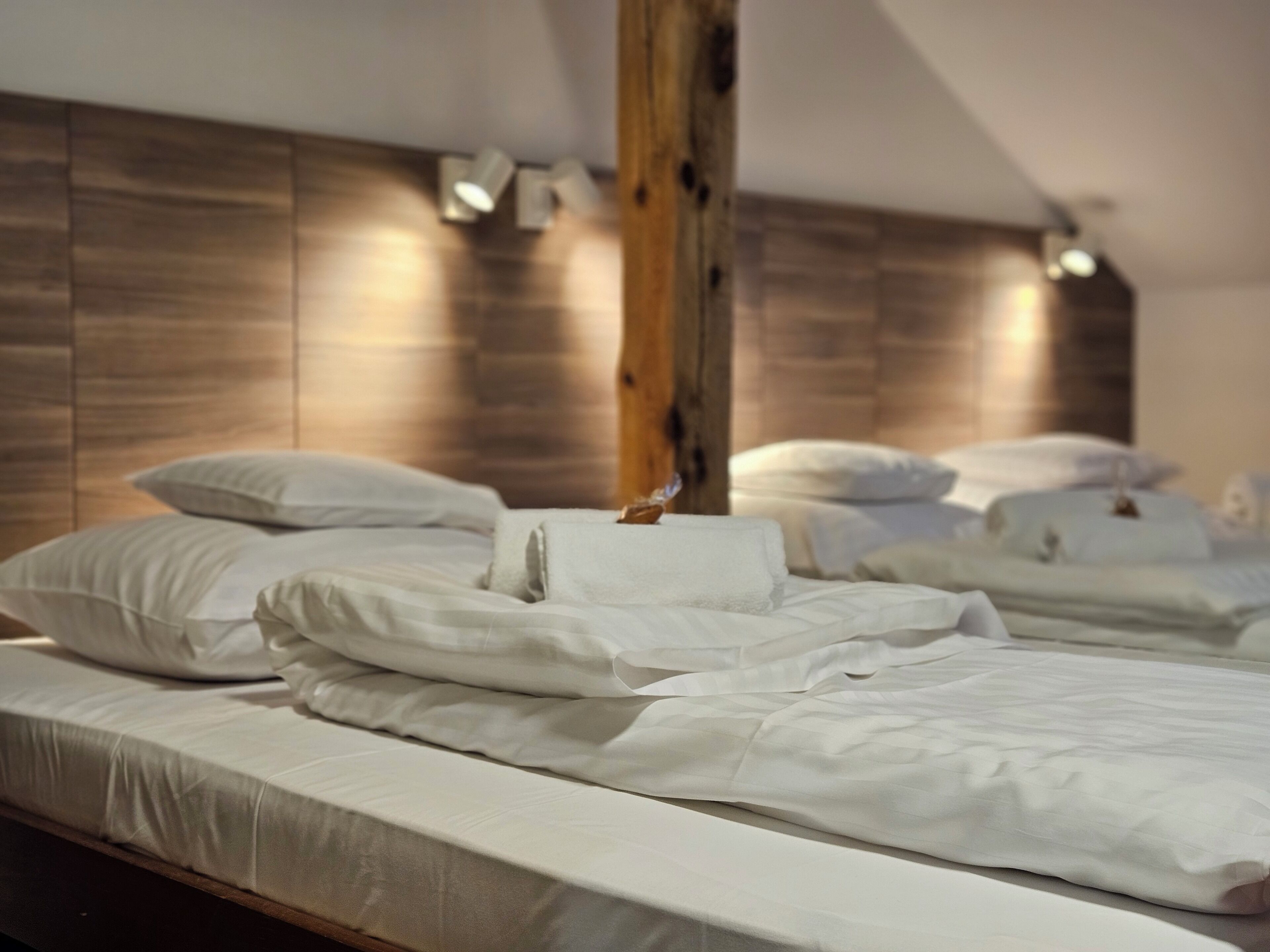 Ein Schlafzimmer mit einem Holz-Kopfteil, weißer Bettwäsche und Holzbalken.