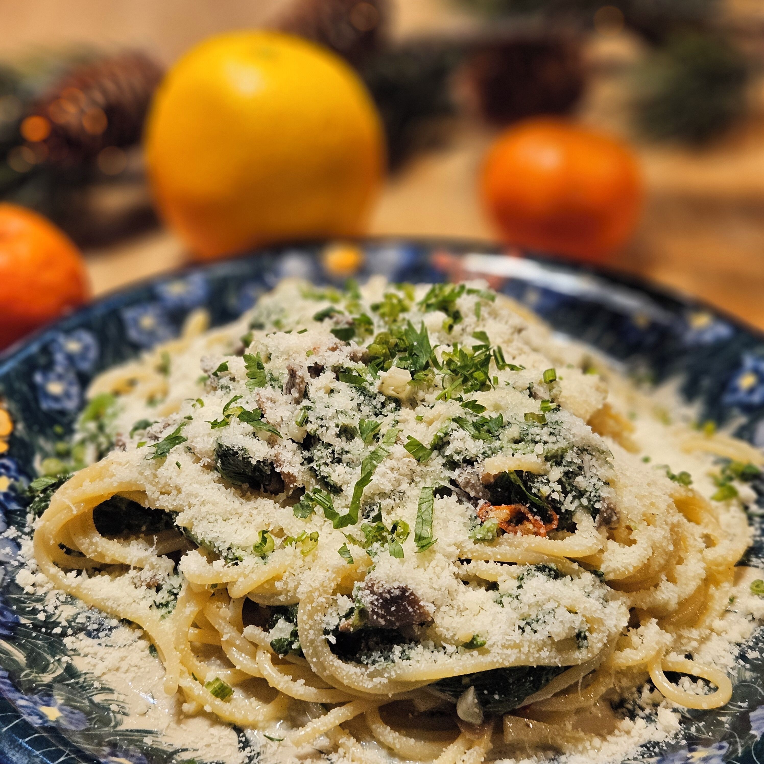 Un plato de pasta con salsa cremosa, adornado con hierbas y queso rallado.