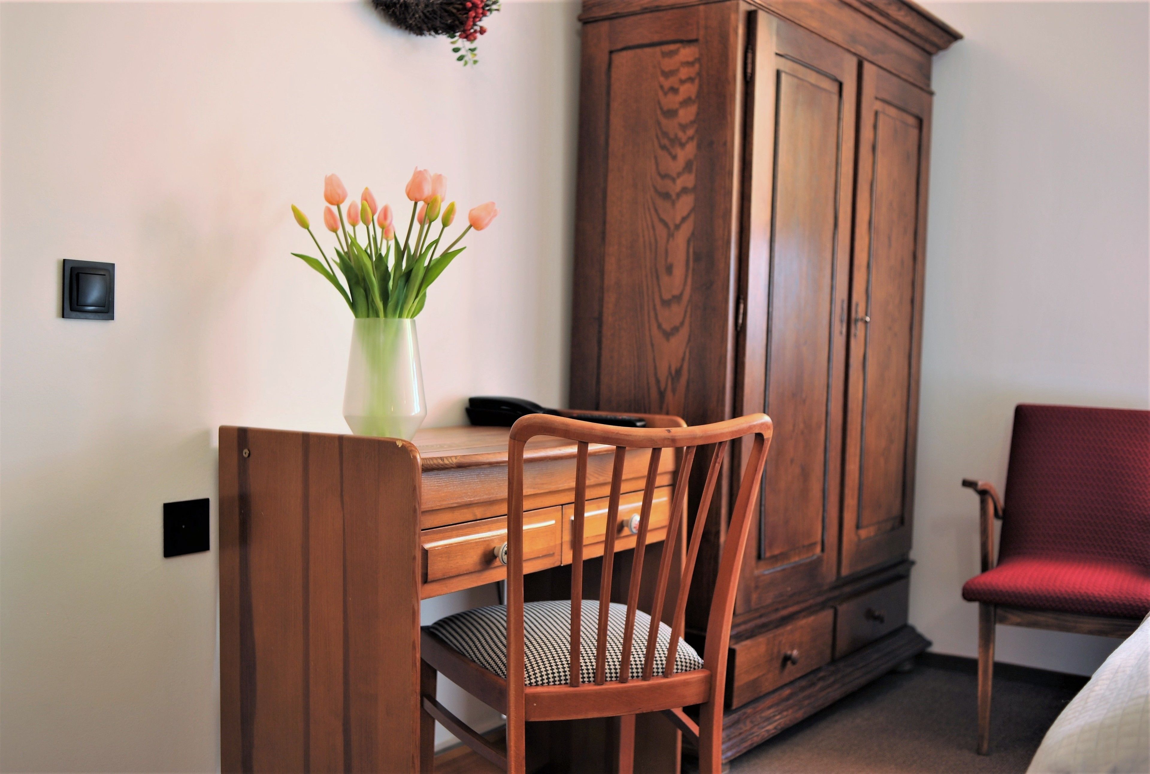 Un bureau en bois, un vase de fleurs, une chaise et un meuble en bois.