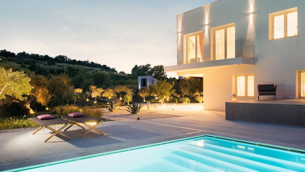 Une maison moderne dotée d’une piscine, d’un espace salon extérieur et d’une terrasse bien éclairée.