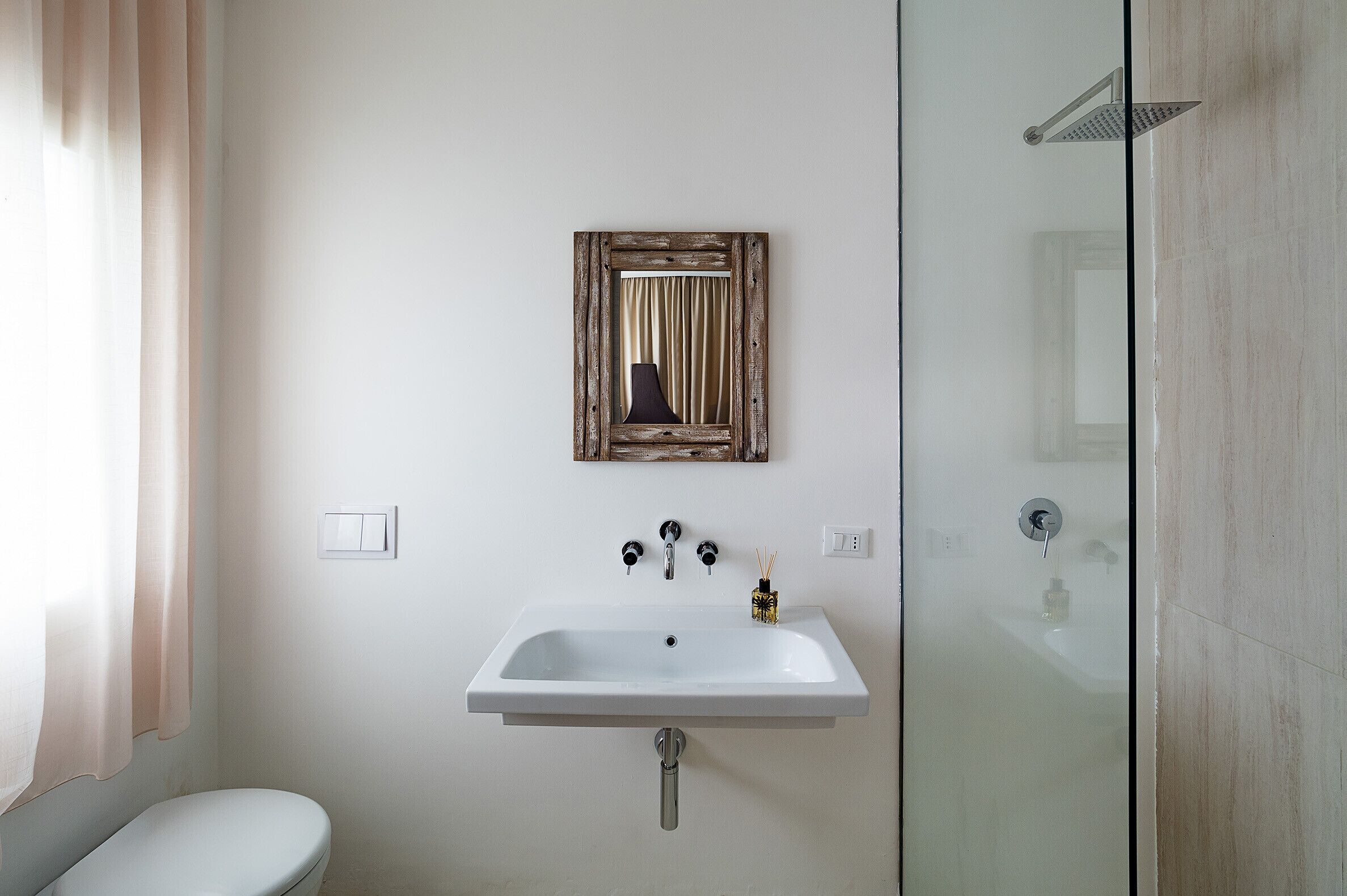 A bathroom with a white sink, a mirror, and a shower.