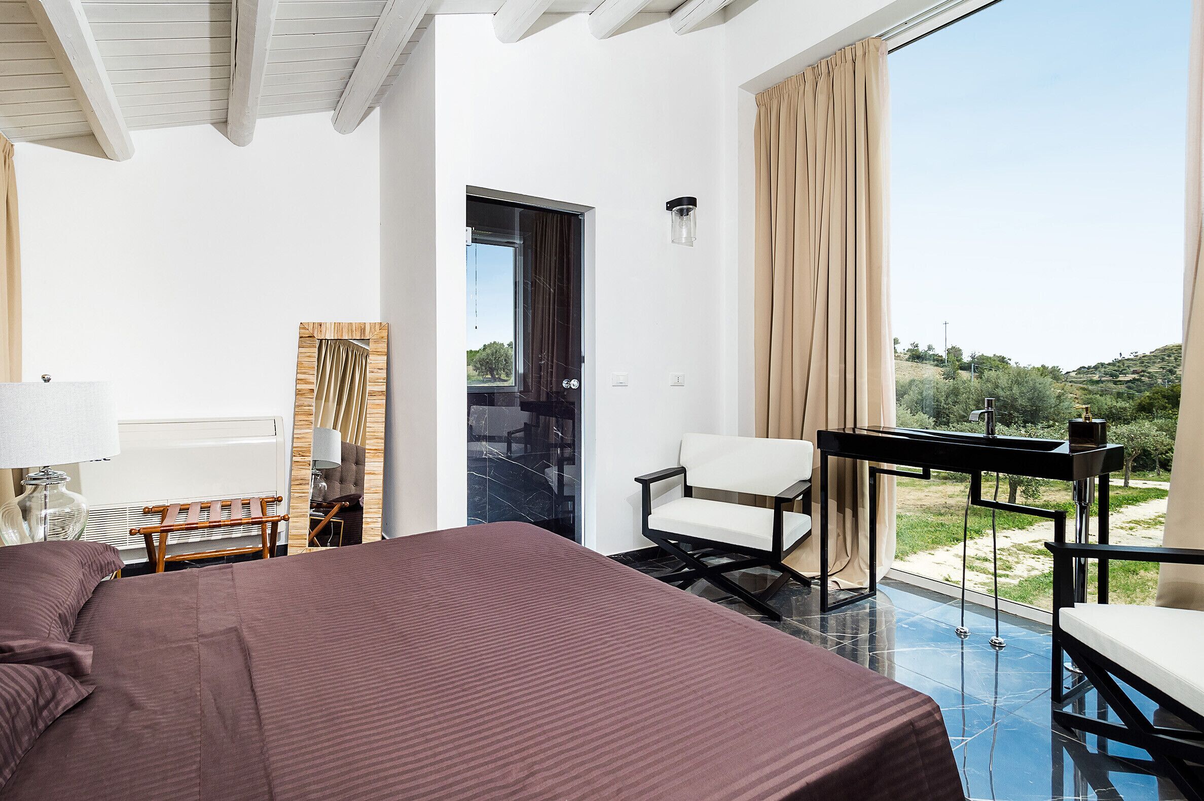 Habitación de hotel moderna con una cama grande, un escritorio, una silla y vistas al exterior.