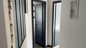 A hallway with a dark door, a light switch, and a framed picture on the wall. - ILE TUDY - Contemporary house 6 places with garden 100m from the beach (Île-Tudy)