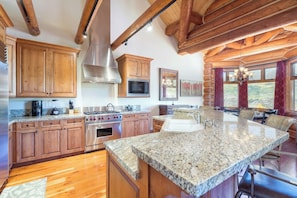 A spacious kitchen with wooden cabinets, granite countertops, and a large island.